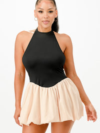 Model wearing a Bubble Mini Dress featuring a halter neckline and a bubble skirt in classic black and beige.