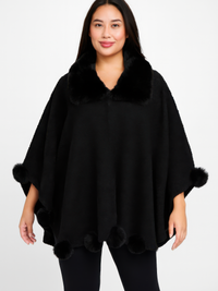 Trim Cape With Faux Fur Collar model wearing a black bouclé cape with pom trim and faux fur collar.