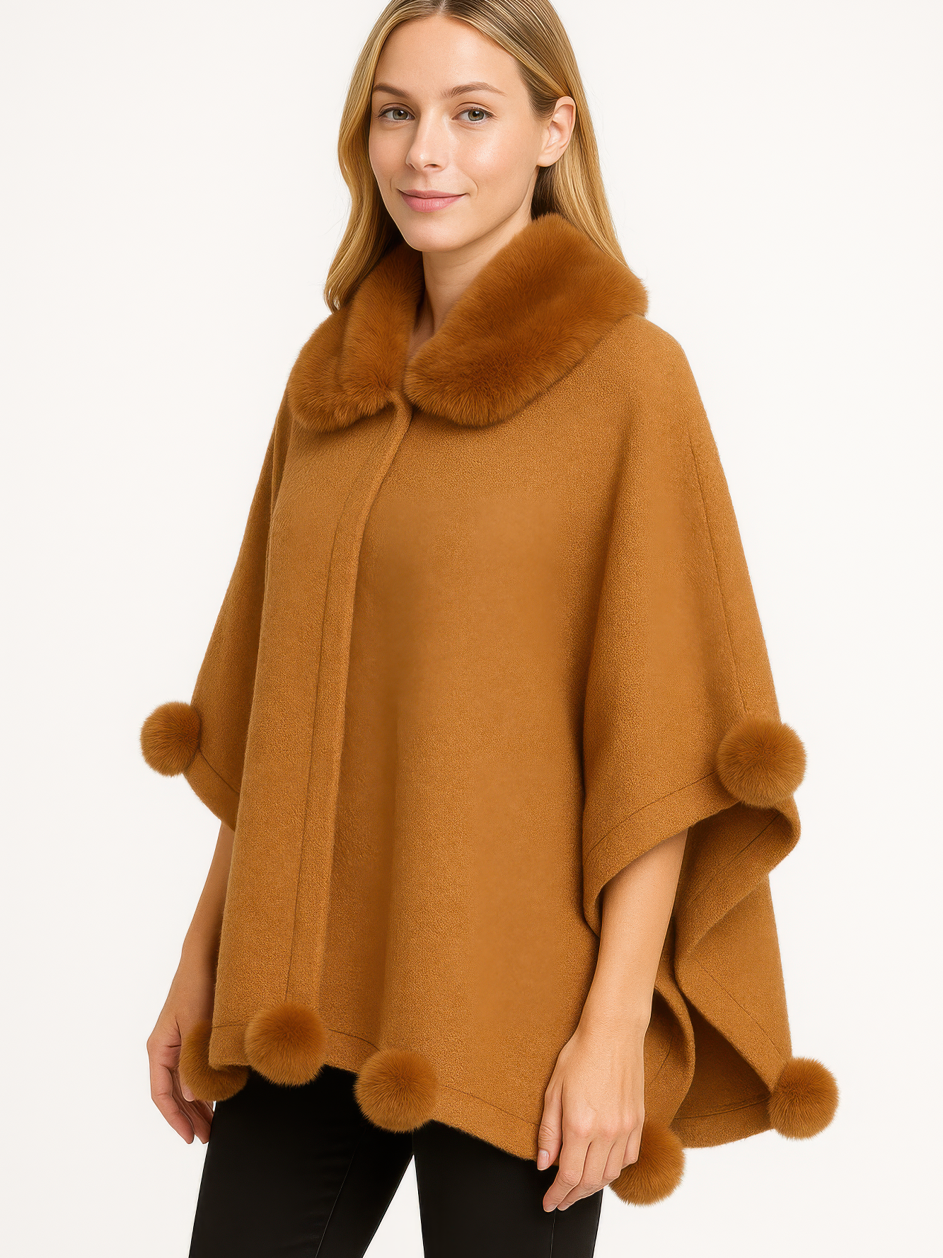Woman wearing a stylish trim cape with faux fur collar and pom trim in a warm color.