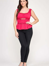 Plus Size Ruffled Tank With Cut Out model wearing pink ruffled tank top paired with black skinny jeans.