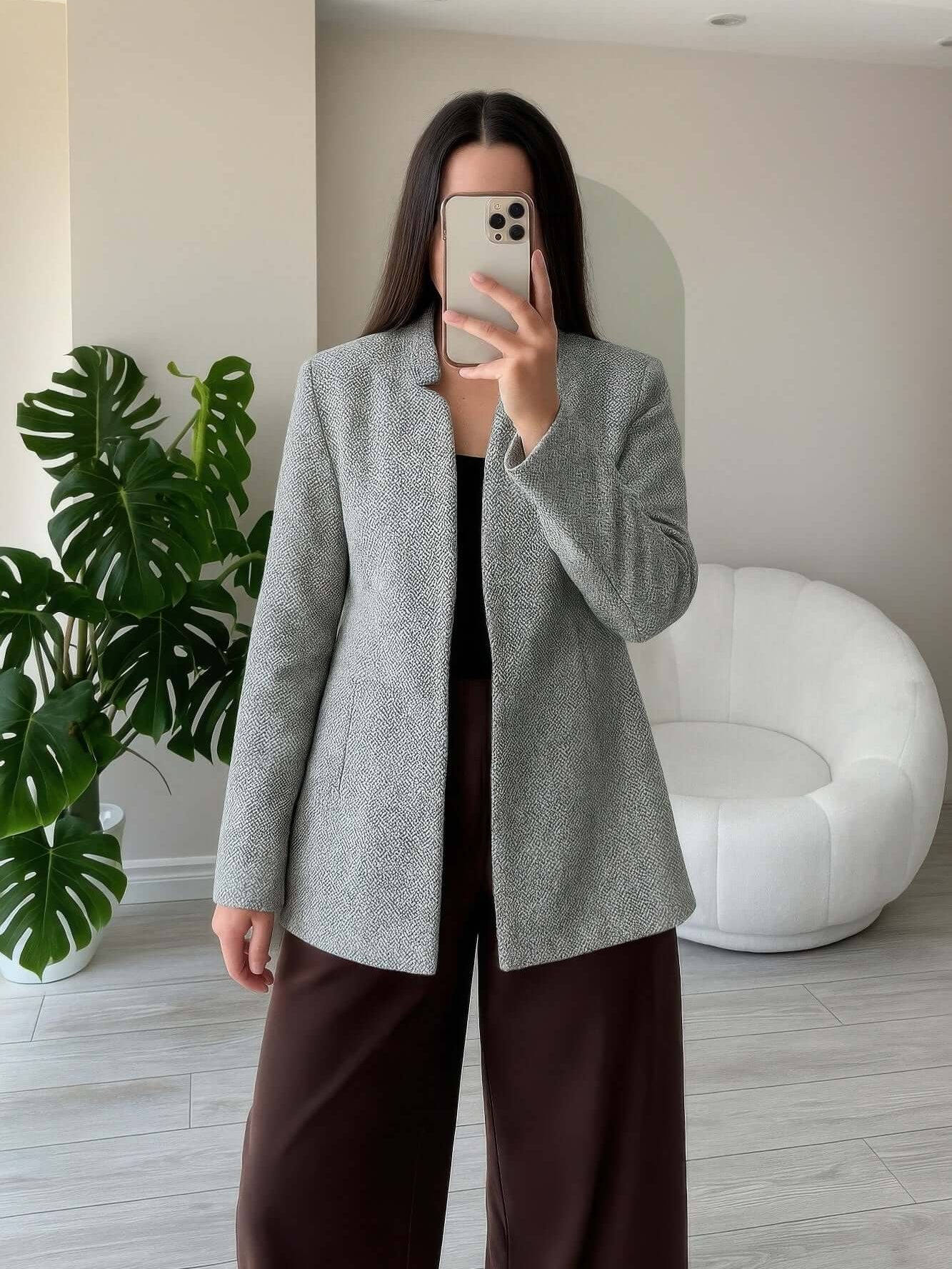 Woman wearing a Pocketed Herringbone Coat Woman in a modern interior, showcasing its stylish design and relaxed fit.