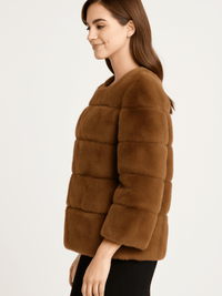 Model showcasing the Plush Camel Faux Fur Jacket in a side profile, featuring a collarless neckline and horizontal paneling.