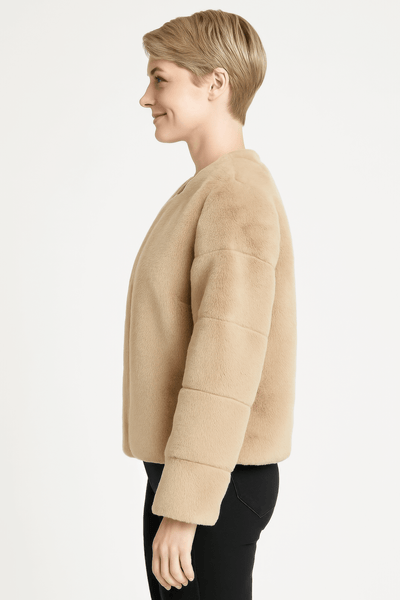 Side view of a woman wearing a beige faux fur jacket, showcasing its plush design and modern fit.
