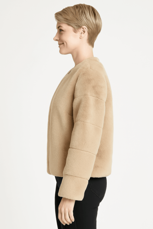 Side view of a woman wearing a beige faux fur jacket, showcasing its plush design and modern fit.