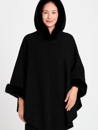 Hooded Faux Fur Trim Cape worn by a woman, showcasing its luxurious black fabric and plush faux fur trim.