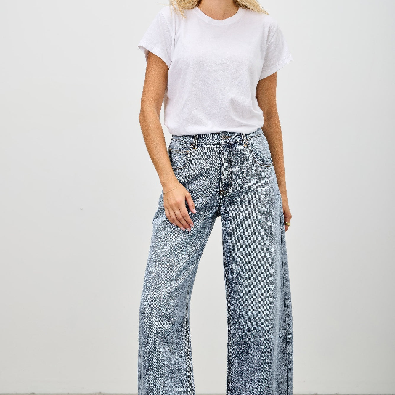 Model wearing High Rise Low Curve Barrel jeans with a white t-shirt and sneakers, showcasing a modern stylish look.