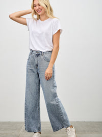 Woman wearing High Rise Low Curve Barrel jeans with a white t-shirt and sneakers, showcasing a modern and stylish silhouette.