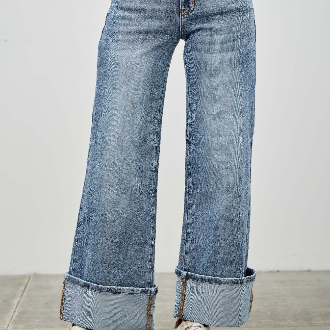 Mid Rise Cuffed Jeans With Stretch in light blue denim, featuring a cuffed hem and paired with stylish sneakers.