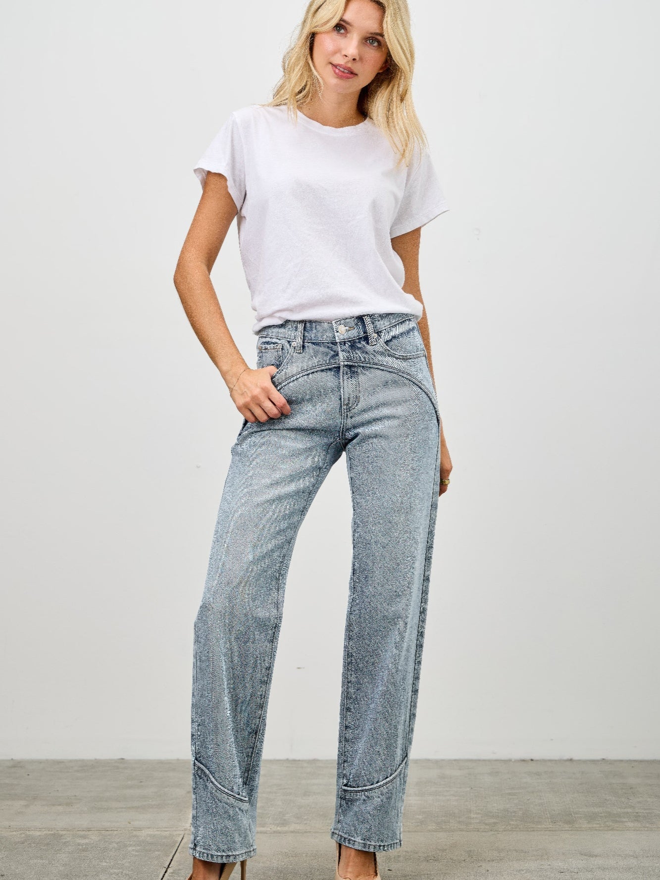 Woman wearing Mid Rise Straight With Piping jeans with a white t-shirt and heels against a plain background.