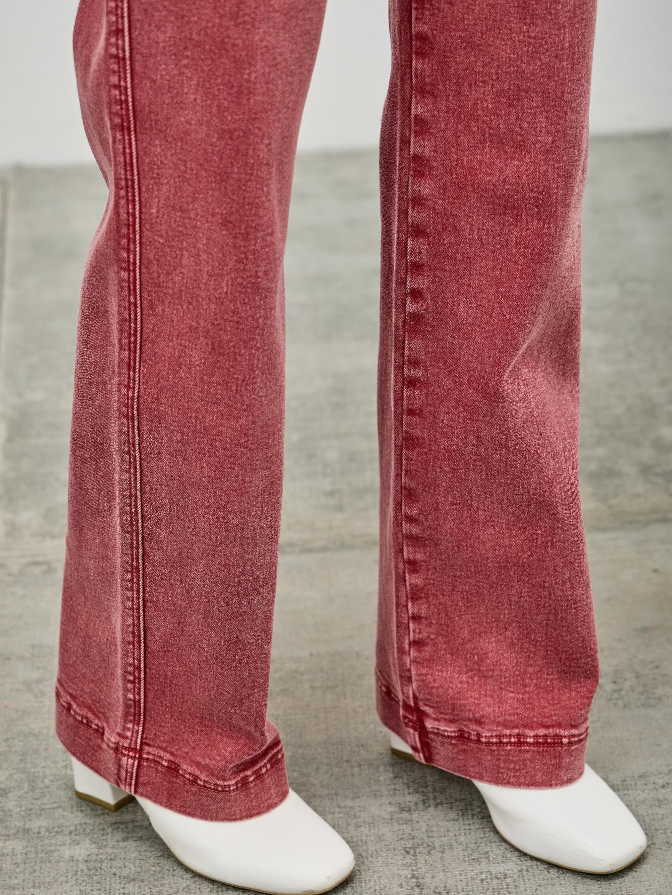 High Rise Slim Wide Straight jeans in red with white ankle boots on a gray floor.