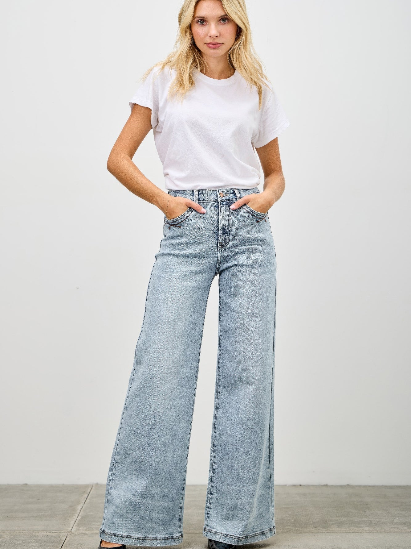 Model wearing High Rise Wide Leg jeans with a white t-shirt, showcasing a stylish denim look.