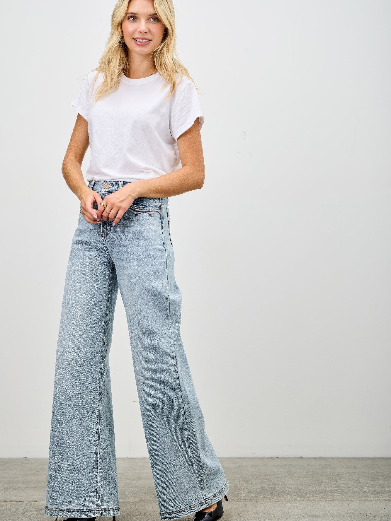 Model wearing High Rise Wide Leg jeans paired with a basic white t-shirt and stylish heels.