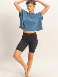 Model wearing an Acid Washed Cross Detail Open Back Top with high-waisted black shorts, showcasing a modern silhouette.