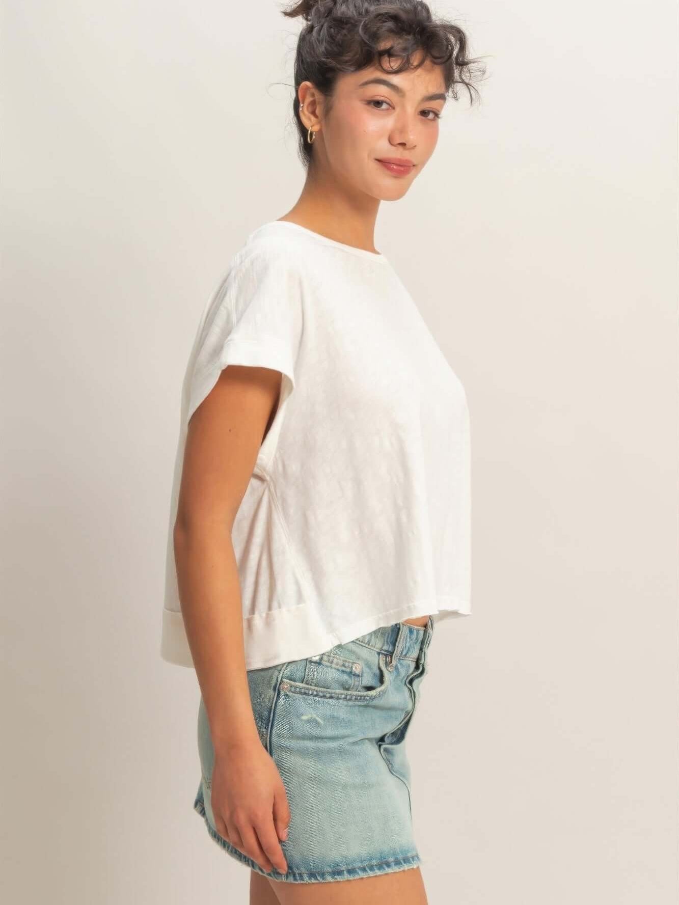 Model wearing Acid Washed Cross Detail Open Back Top with denim shorts, showcasing side view and relaxed fit.