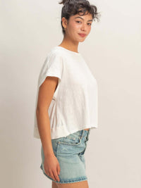 Model wearing Acid Washed Cross Detail Open Back Top with denim shorts, showcasing side view and relaxed fit.