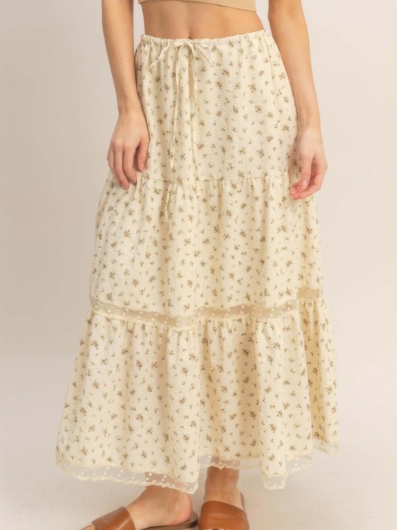 Model wearing a tiered lace trim skirt featuring a floral pattern and adjustable waistband.