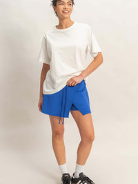 Wrap Front Elastic Waist Skort in blue worn by a model with a white t-shirt and sneakers, showcasing its stylish design.