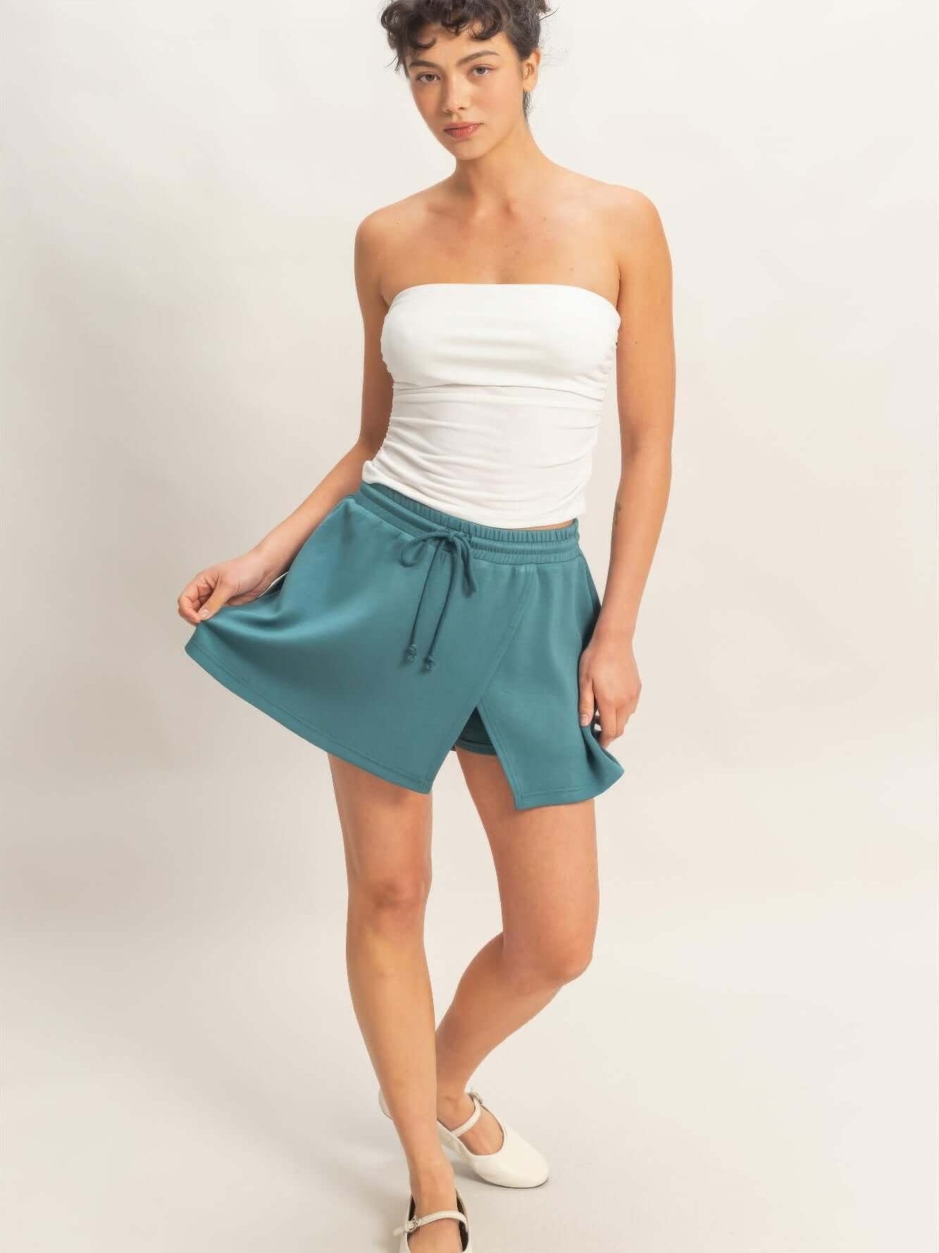 Model wearing a Wrap Front Elastic Waist Skort in teal, showcasing its stylish design and comfortable fit.
