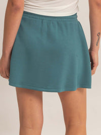 Back view of a woman wearing a wrap front elastic waist skort in teal, showcasing the elastic waistband and soft fabric.