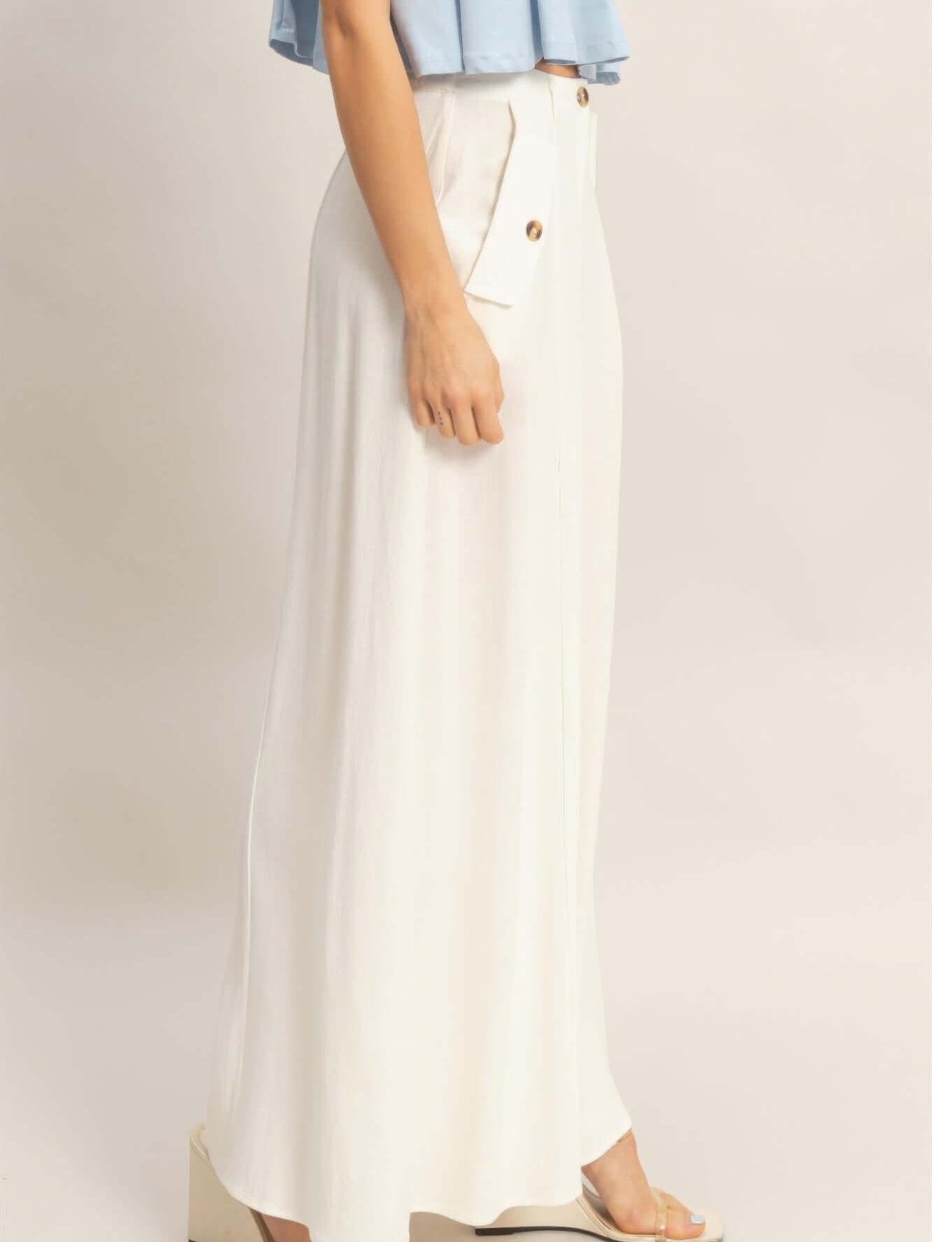 Wide-leg Flap Pocket Pants shown with a blue top, highlighting a side view of the structured silhouette and pocket details.