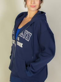 Graphic drop shoulder zipper up hoodie in navy with Brooklyn logo, worn casually by a model.