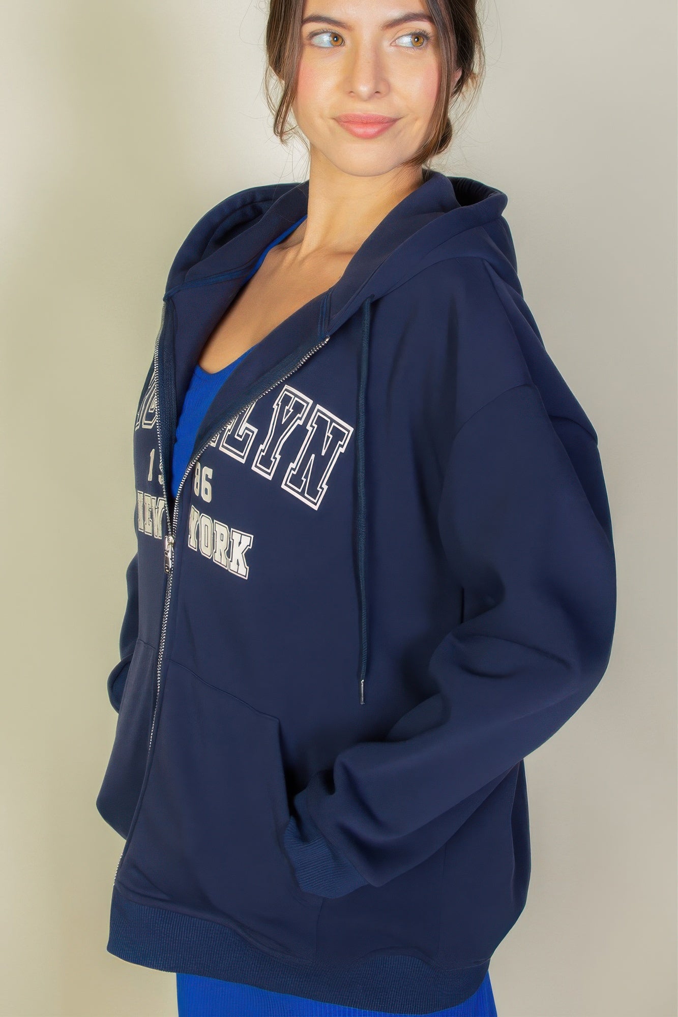 Graphic drop shoulder zipper up hoodie in navy with Brooklyn logo, worn casually by a model.