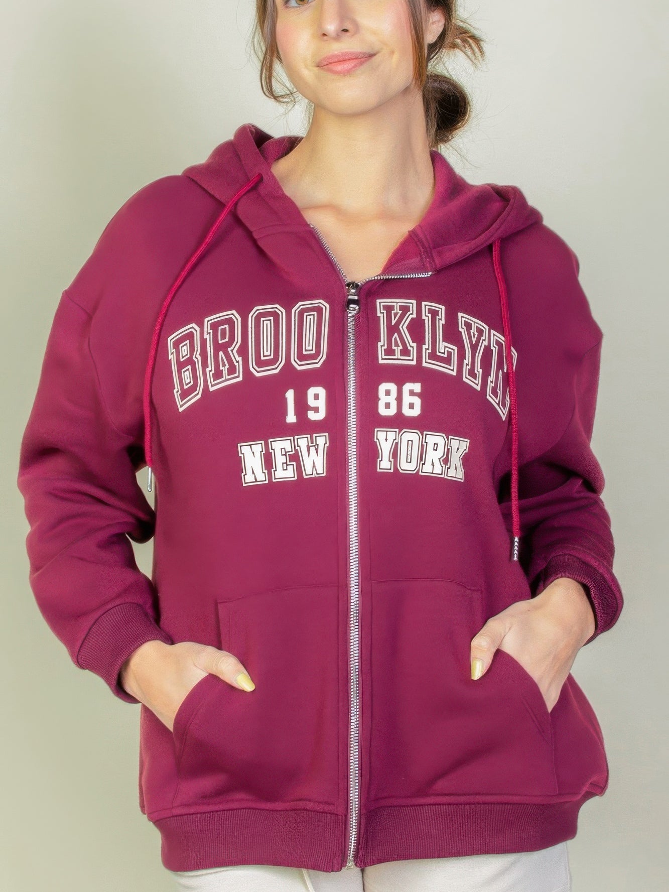 Model wearing a burgundy Graphic Drop Shoulder Zipper Up Hoodie featuring Brooklyn logo, perfect for casual style.