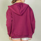 Back view of a burgundy graphic drop shoulder zipper up hoodie against a neutral background.