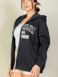 Model wearing a black Graphic Drop Shoulder Zipper Up Hoodie with Brooklyn logo, showcasing casual style and comfort.