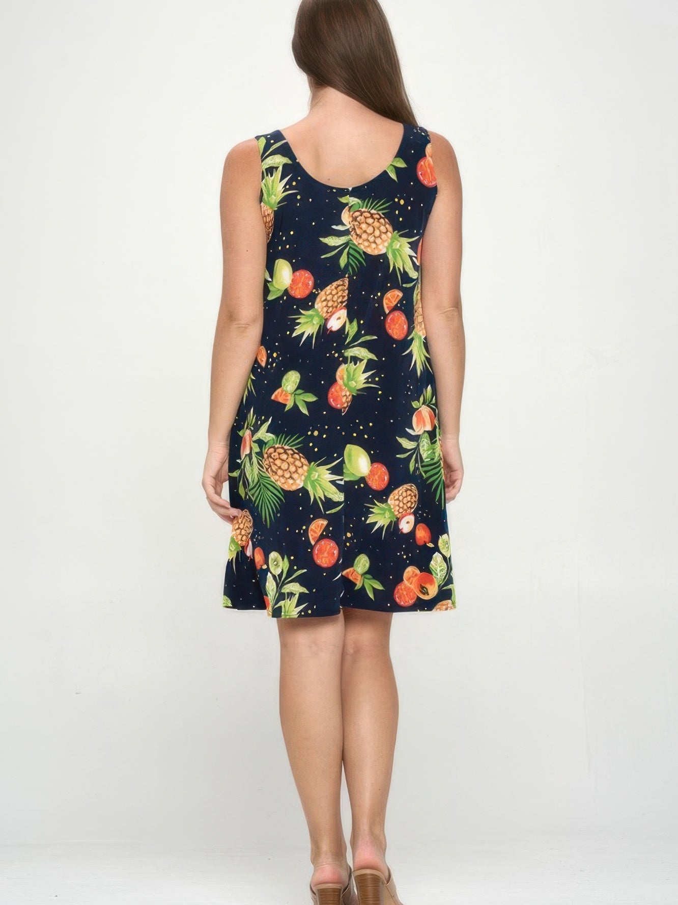 Back view of a woman wearing a Plus Size BNS Print Missy Tank Dress with vibrant fruit prints on a navy background.