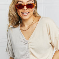 Woman wearing Oval Full Rim Sunglasses with an elegant outfit and a smile.