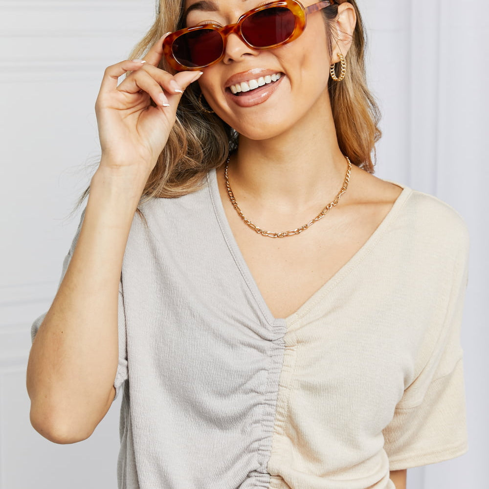 Oval Full Rim Sunglasses worn by a smiling woman with stylish outfit and accessories.