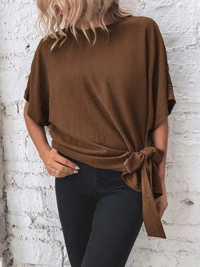 Knotted Round Neck Half Sleeve Blouse in brown worn with black jeans, showcasing its tied design on a model.