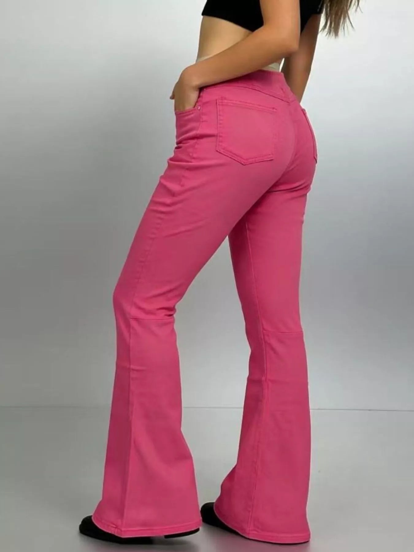 Model showcasing High-Waisted Flare Jeans in pink with a close view of the back and flared legs.
