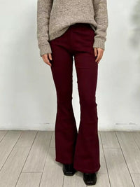 Model wearing High-Waisted Flare Jeans in a burgundy color, paired with a beige sweater, showcasing the design and fit.